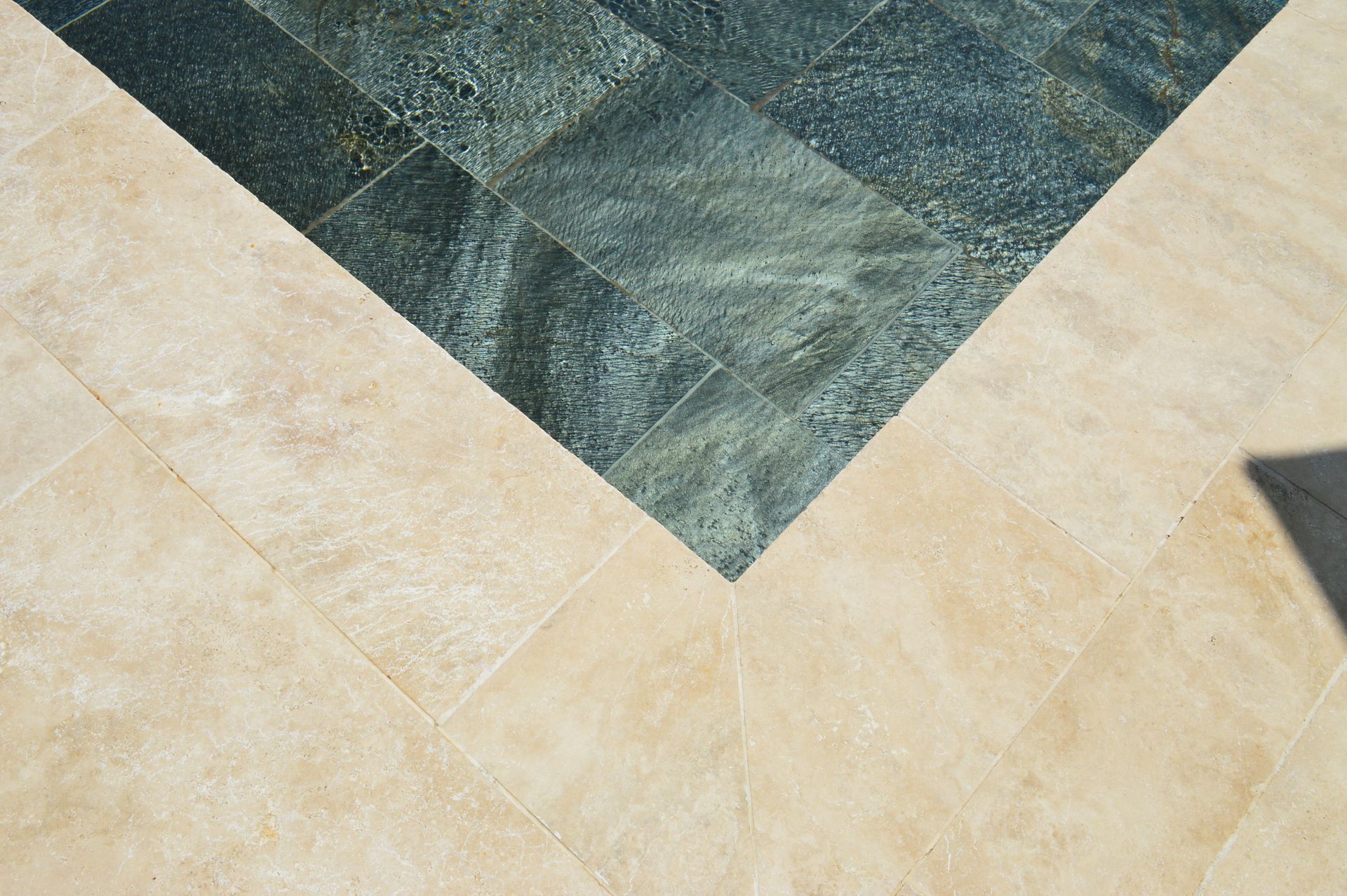 Gros plan sur des carreaux de sol en pierre beige et gris foncé formant un motif géométrique