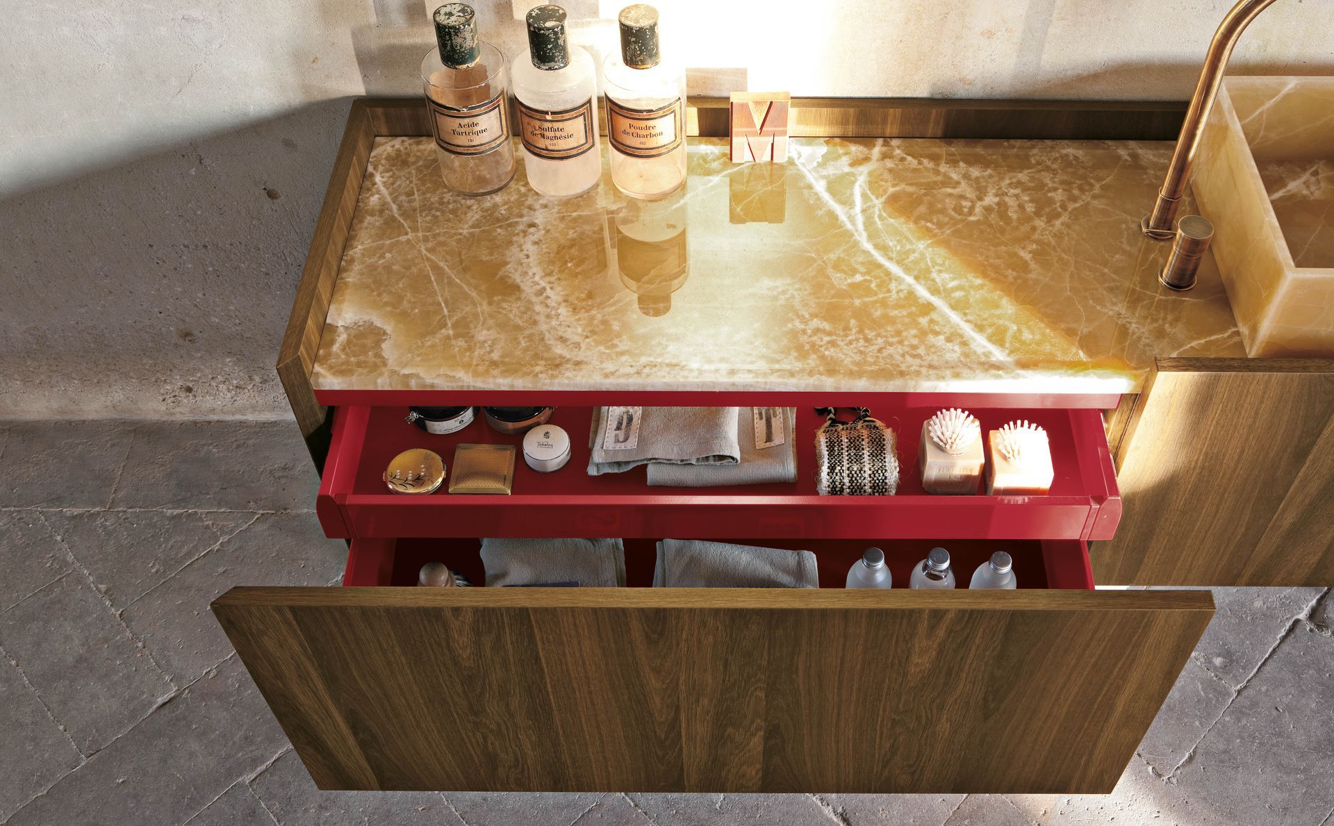 Armoire ouverte contenant des articles de toilette et des flacons sur un comptoir doré dans une salle de bain