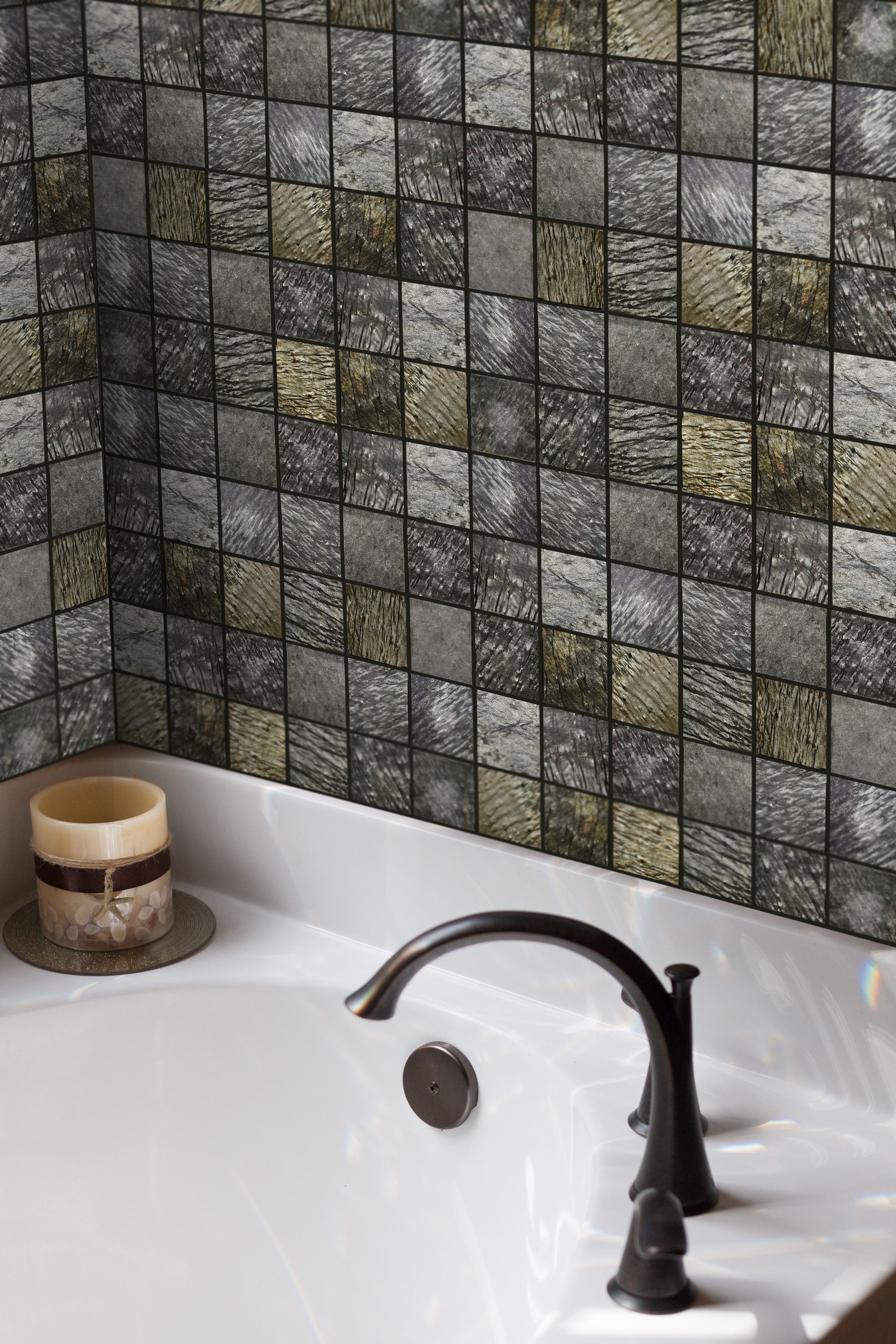 Lavabo de salle de bain avec robinet noir et crédence en mosaïque grise, plus une bougie sur le comptoir
