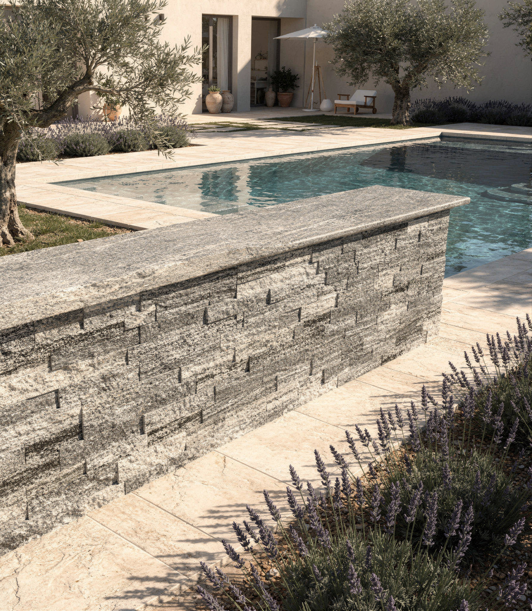 Terrasse en pierre au bord de la piscine, avec une piscine turquoise et une maison moderne en arrière-plan.