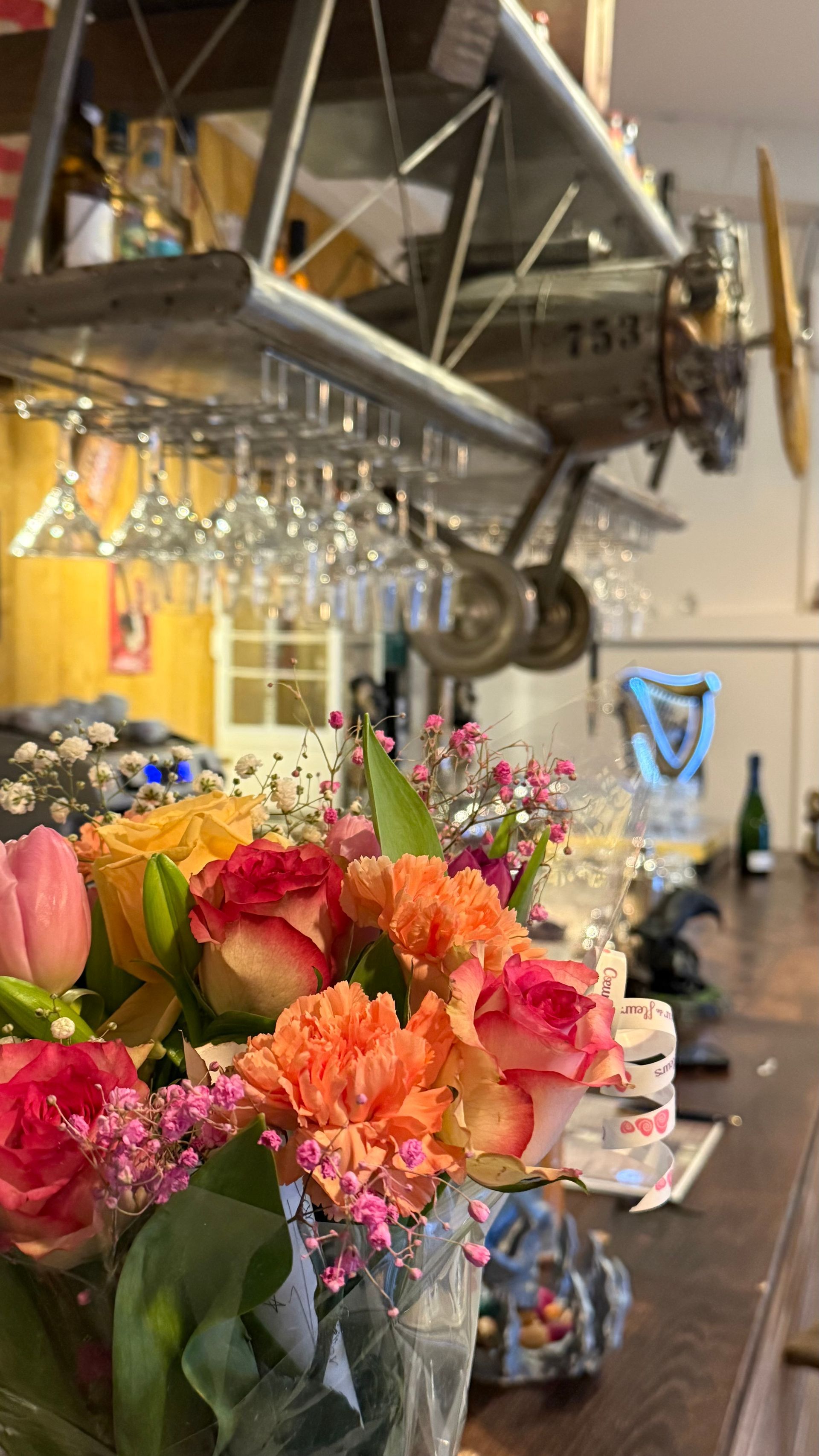 Le comptoir du bar avec des fleurs et des verres à pied.