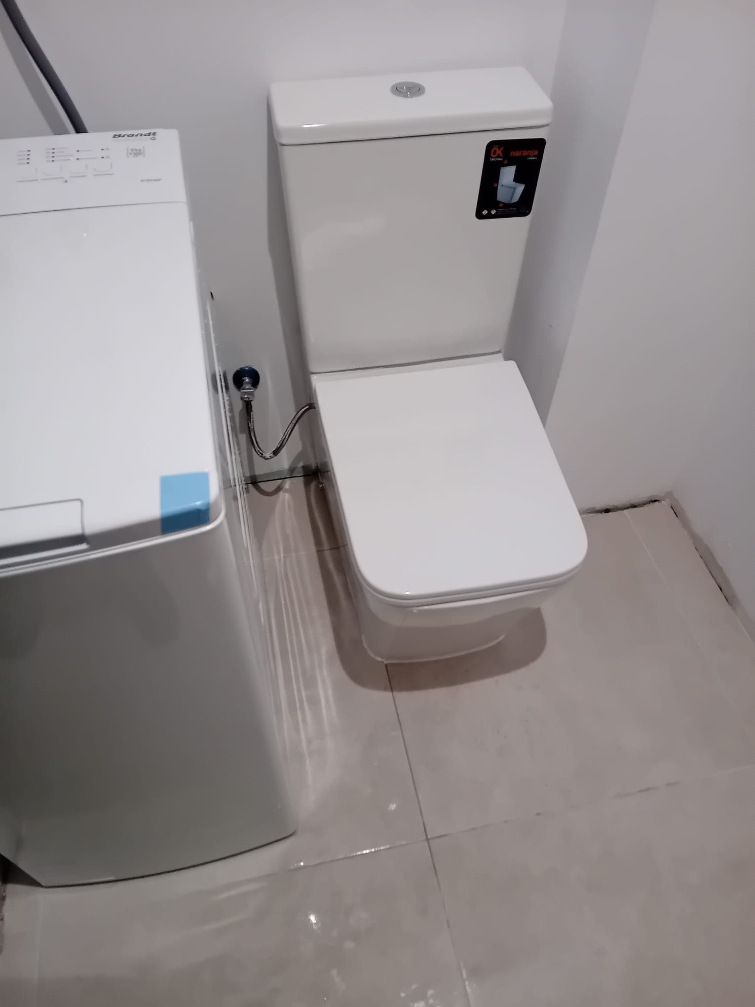 Un inodoro está al lado de una lavadora en un baño.