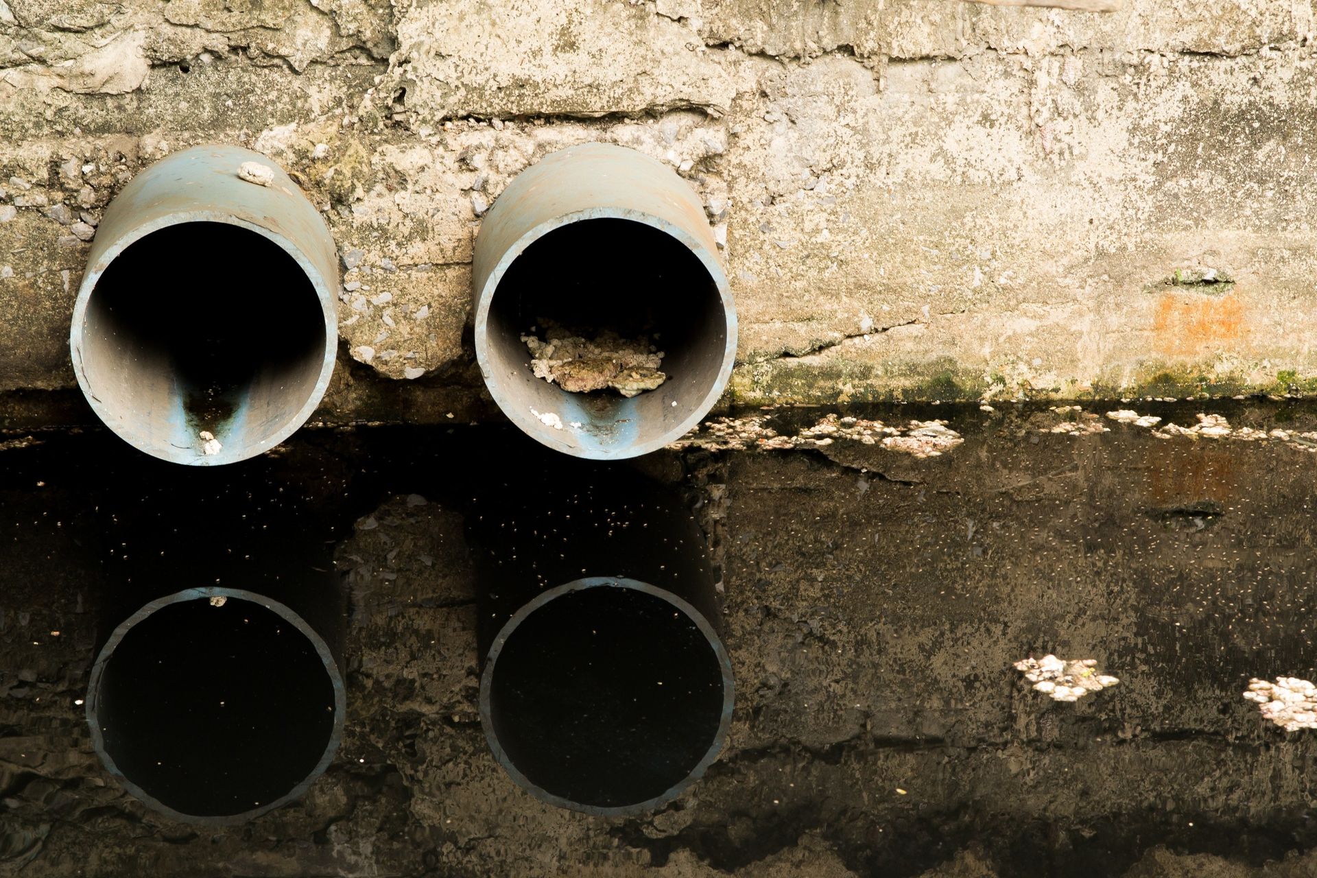 Un par de tuberías están una al lado de la otra en un charco de agua.