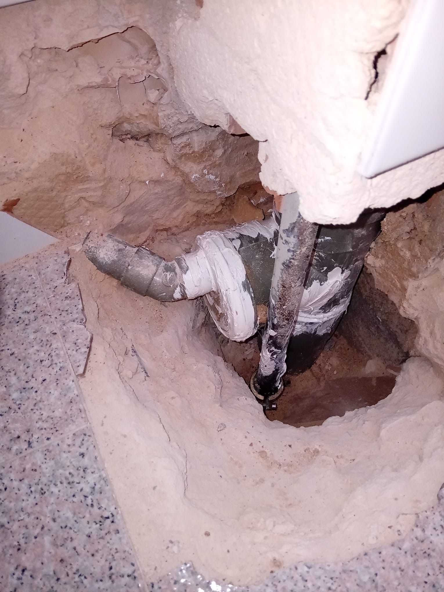 Una tubería sale de un agujero en la pared.