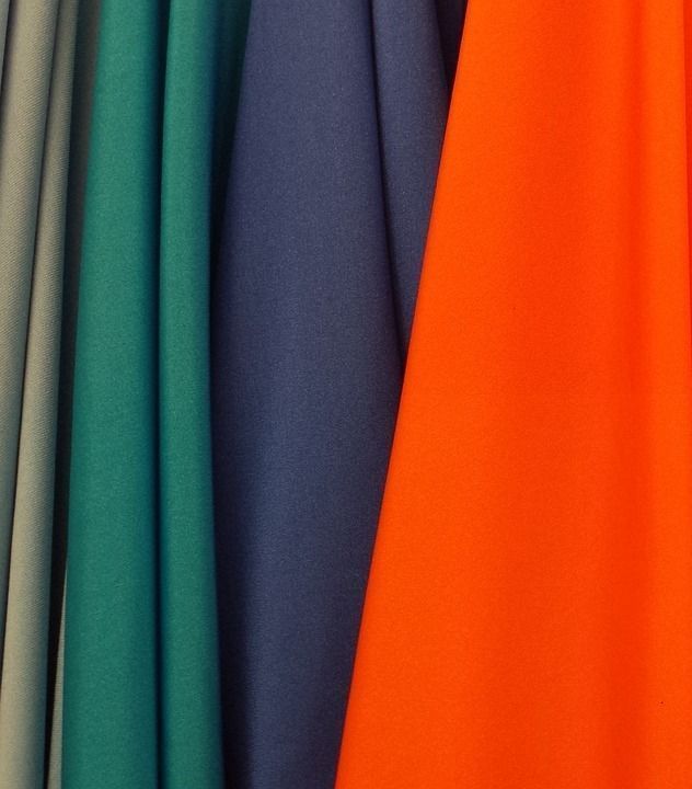 Un montón de telas de diferentes colores están apiladas una encima de otra.