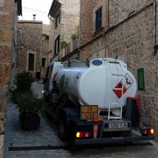 Un camión cisterna blanco está estacionado en un callejón estrecho