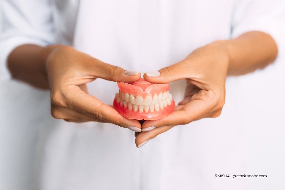 Mitarbeiter von Rink Berthold Zahnarztpraxis hält Gebiss in der Hand