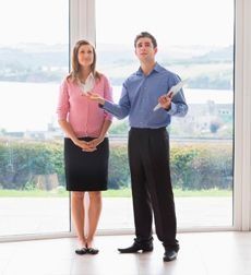 Un hombre y una mujer están parados uno al lado del otro frente a una ventana.