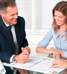 Un hombre y una mujer están sentados en una mesa mirando un plano.