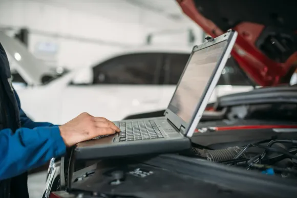 Mecánico que utiliza una computadora portátil para el diagnóstico de un automóvil en un taller