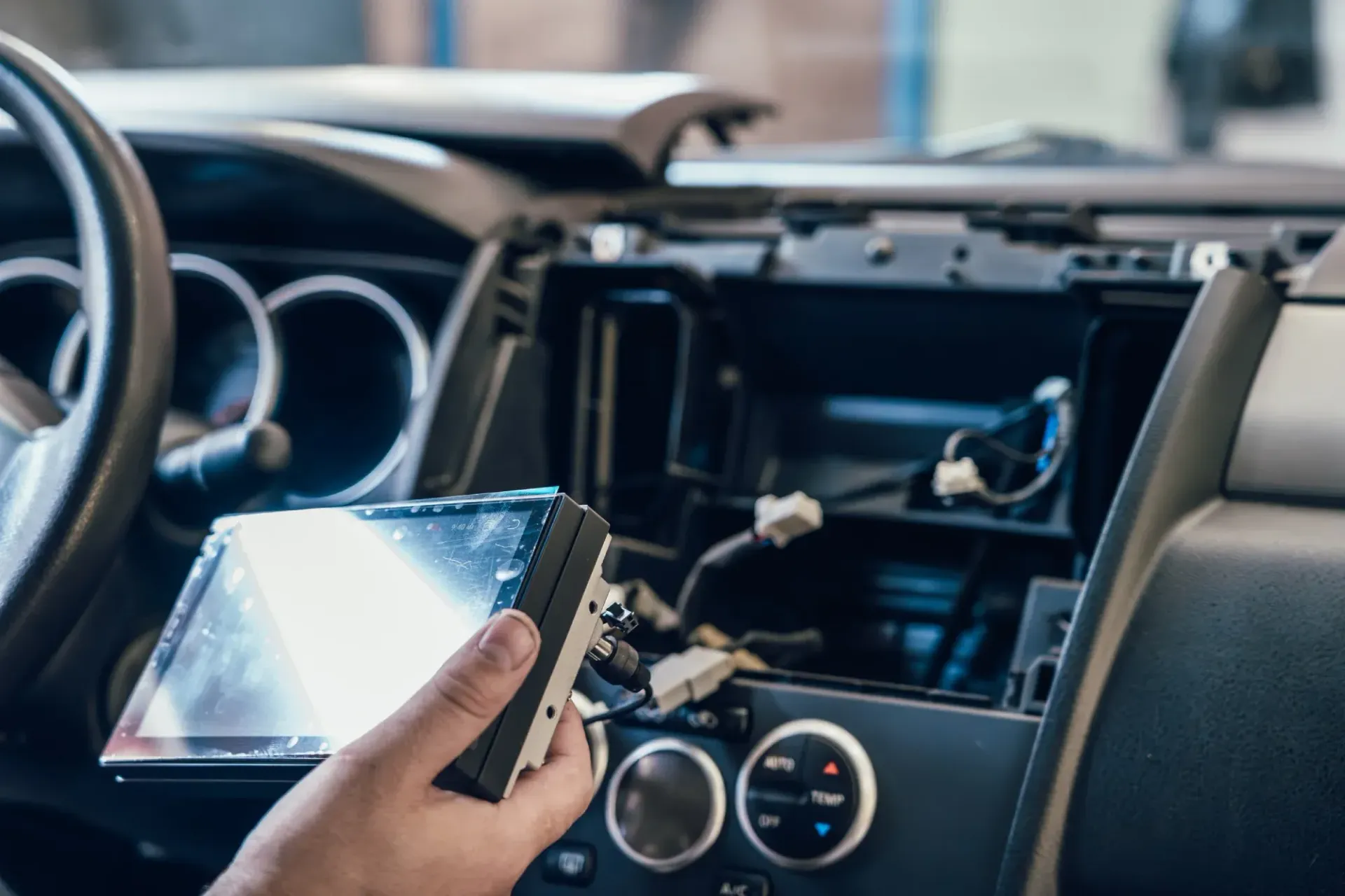 Persona instalando un estéreo de automóvil; el tablero está desarmado, mostrando el cableado y los componentes.
