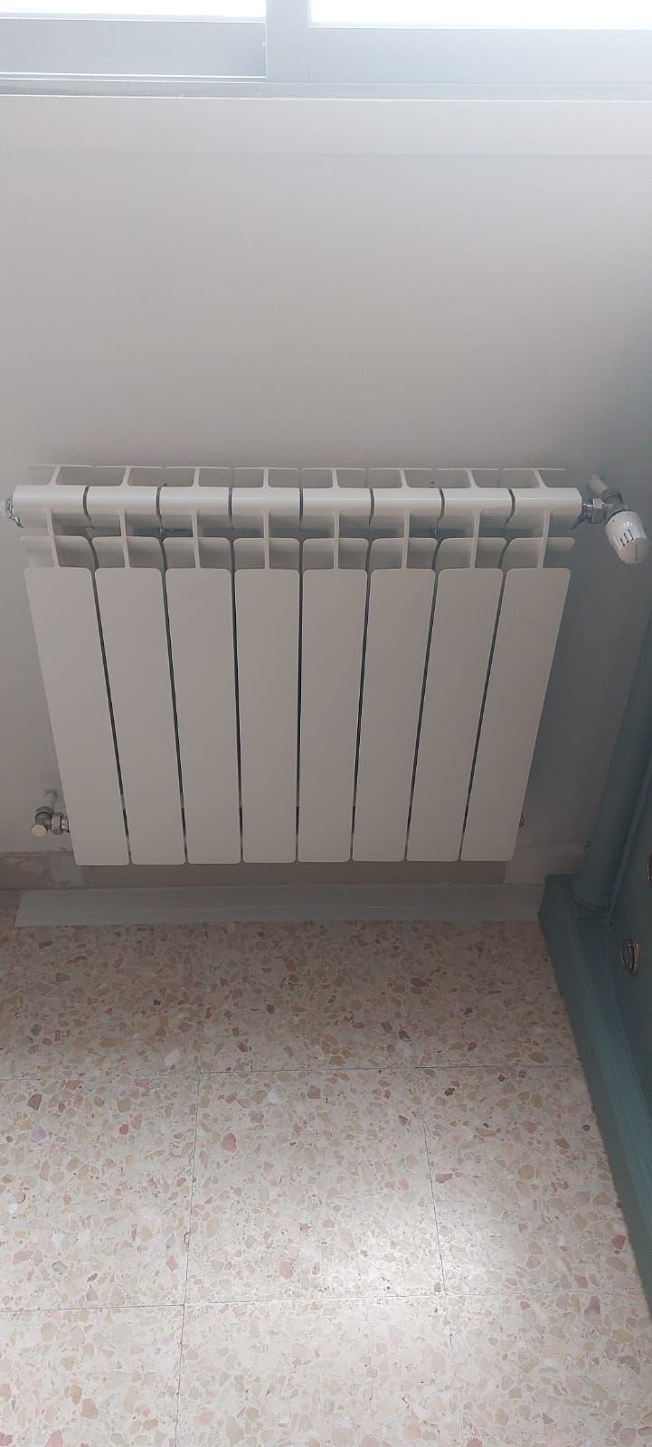 Un hombre con mono inspecciona una unidad de aire acondicionado montada en la pared, con las manos extendidas hacia las rejillas de ventilación.