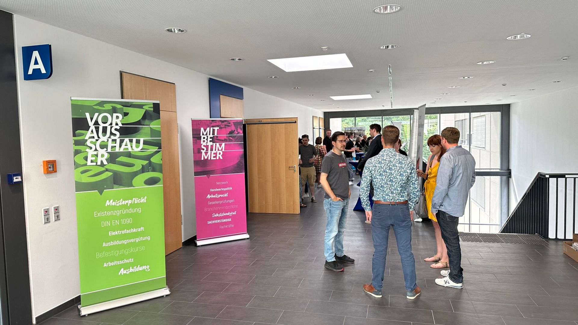 Eine Gruppe von Menschen steht in einem Flur und unterhält sich.