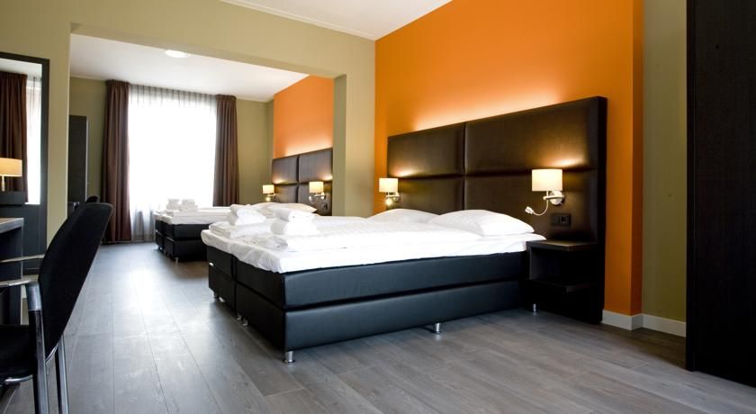 Ein Hotelzimmer mit drei Betten und einem Schreibtisch