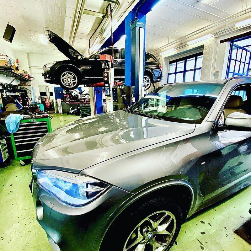 Garage Baggieri – zwei dunkle Autos in der Werkstatt