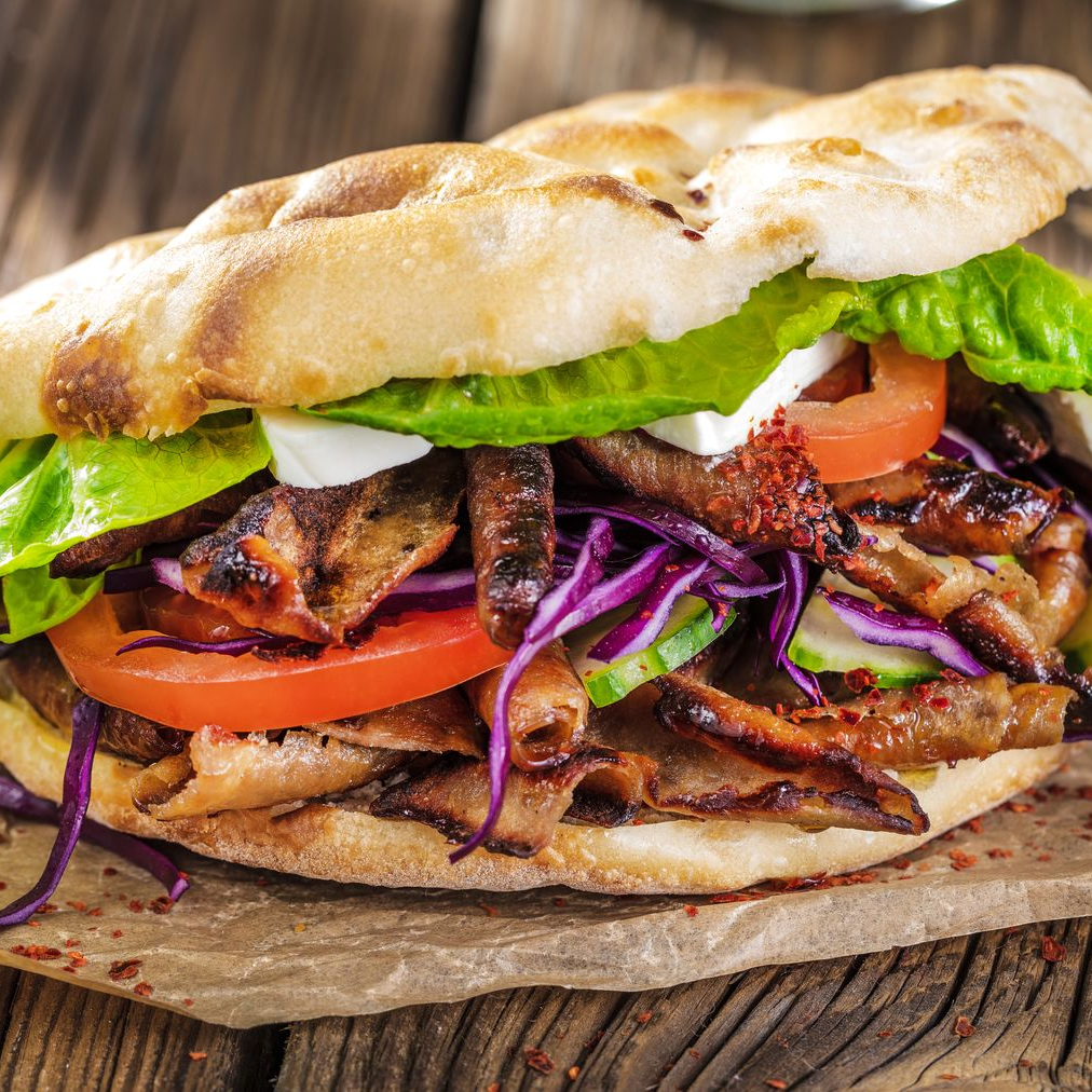 Sandwich grillé avec laitue, tomate, chou rouge et viande sur pain rustique.