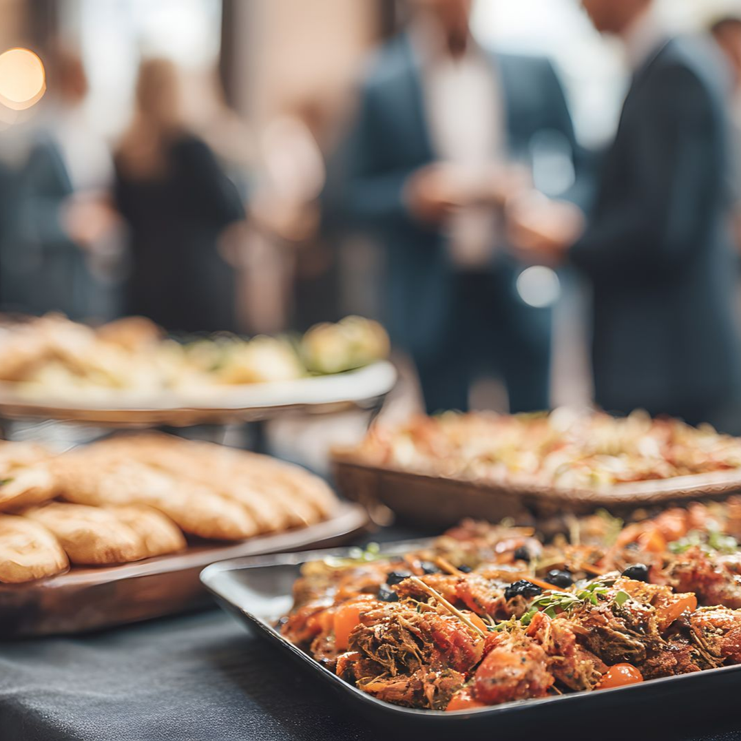 Buffet avec amuse-gueules et pâtisseries présentés à l'assiette lors d'une réunion sociale intérieure floue.