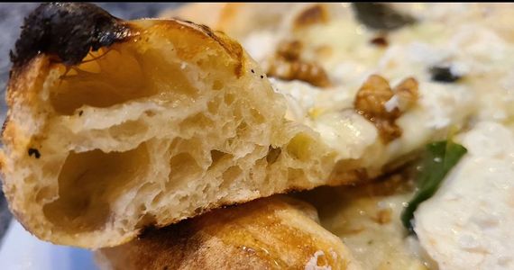 Gros plan sur une tranche de viennoiserie ou de pain doré, garnie d'une crème blanche et de feuilles vertes.