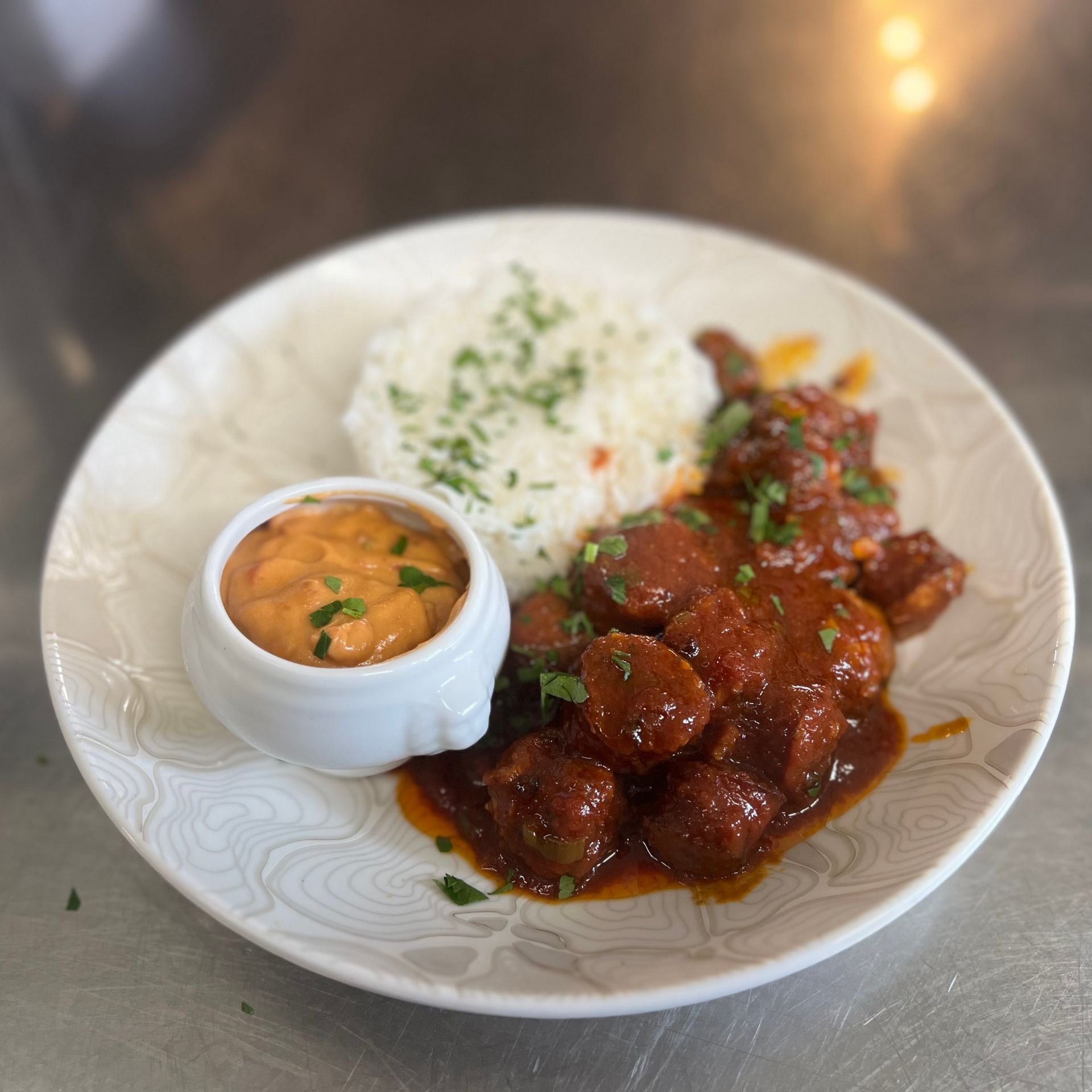 Assiette de boulettes de viande glacées avec du riz blanc et une petite coupelle de sauce à l'orange.