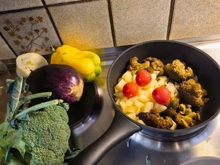 Una pentola piena di verdure è posta sul fornello.