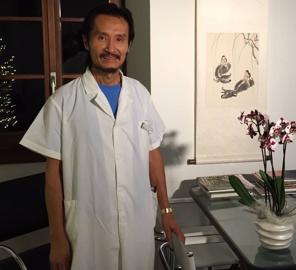 Un uomo in camice è in piedi davanti a un tavolo con dei fiori sopra