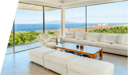 Una sala de estar con muchas ventanas y vista al mar.