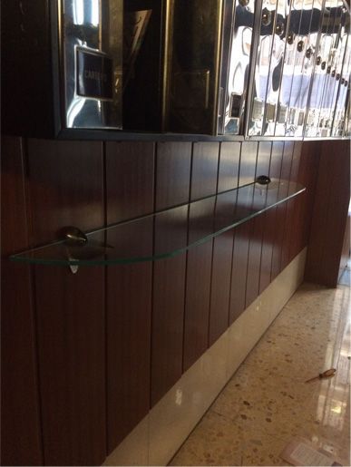 Un estante de vidrio está colgado en una pared de madera.