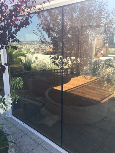 Un patio con una mesa y sillas se refleja en una pared de cristal.