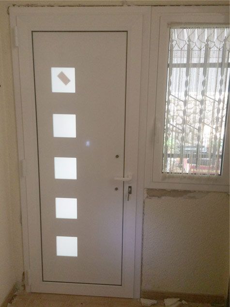 Una puerta blanca con cuadrados y una ventana.