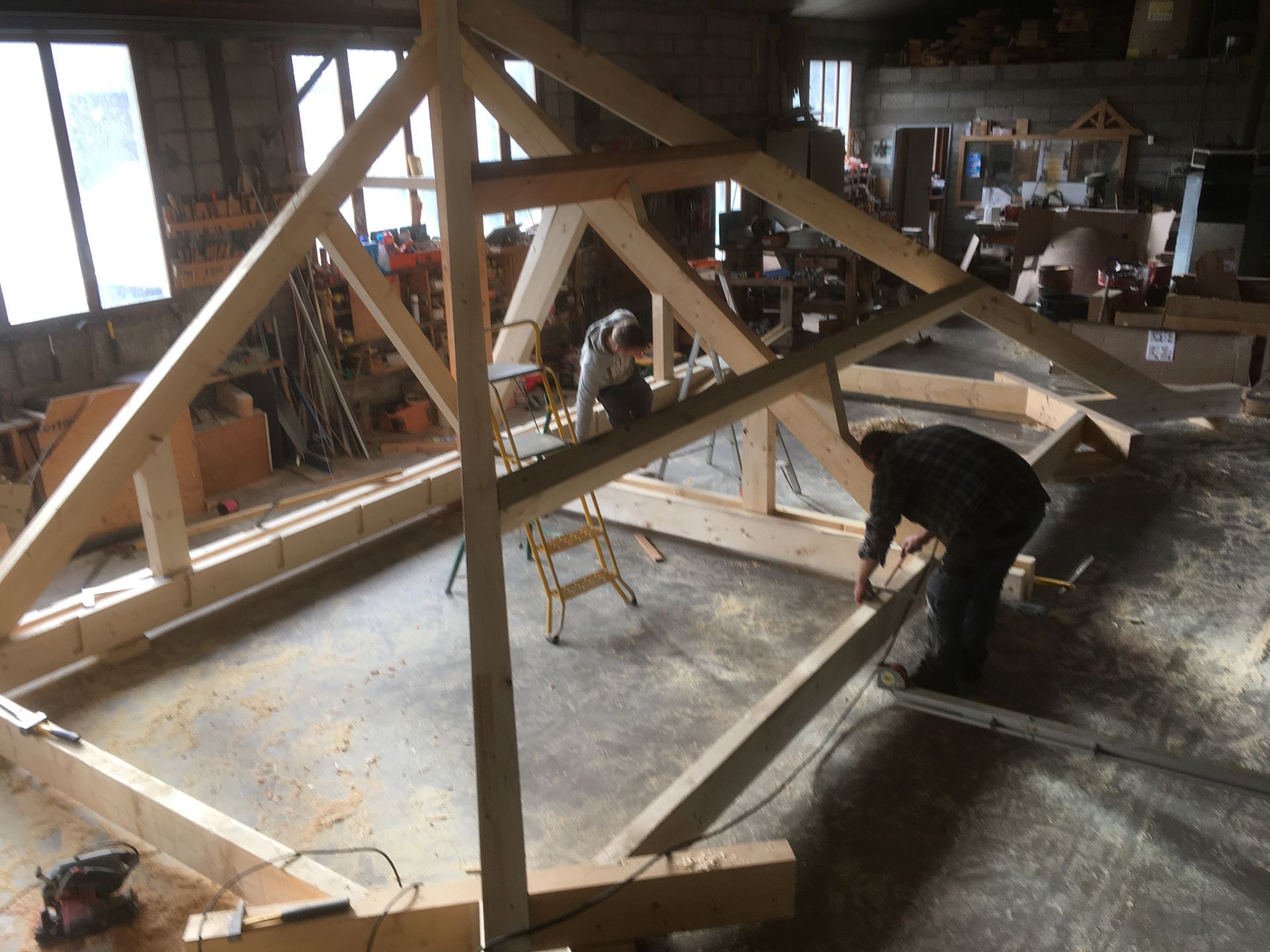 Charpente de toit en bois en construction, adossée à un mur de pierre.