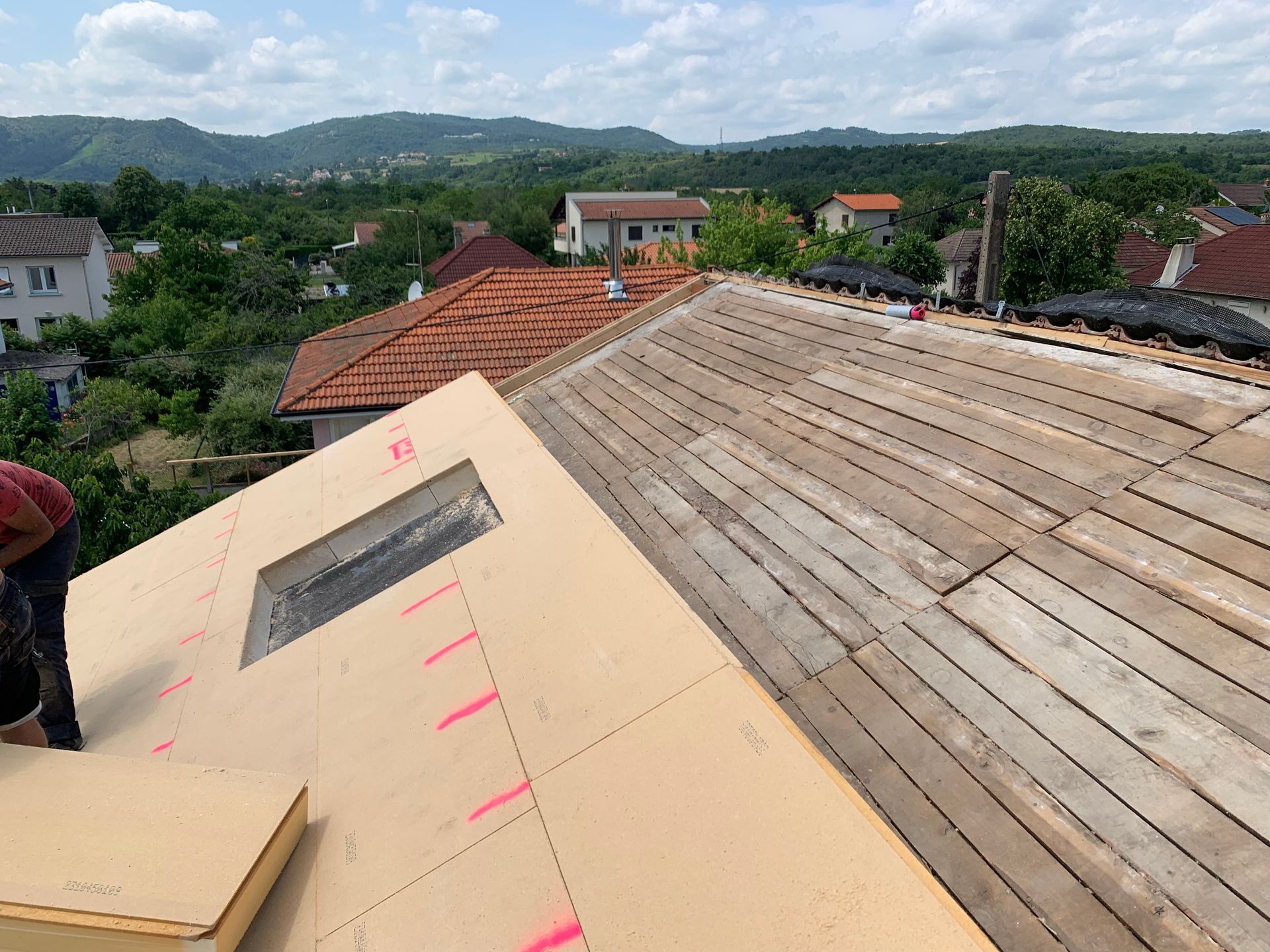 Construction de toiture : pose de panneaux isolants sur une toiture partiellement en bois.