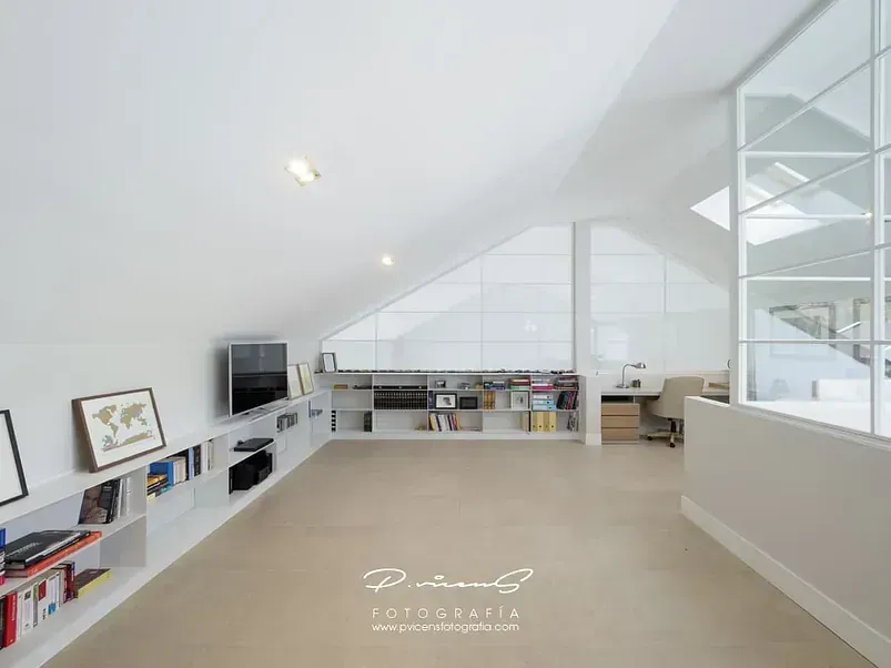 Una sala de estar con techo abovedado y un televisor de pantalla plana en la pared.