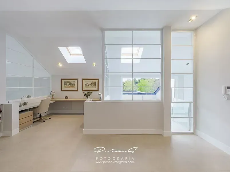 Una habitación con un escritorio y una ventana con tragaluz.