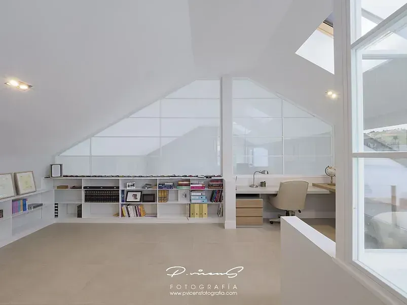 Una habitación con techo inclinado y un escritorio