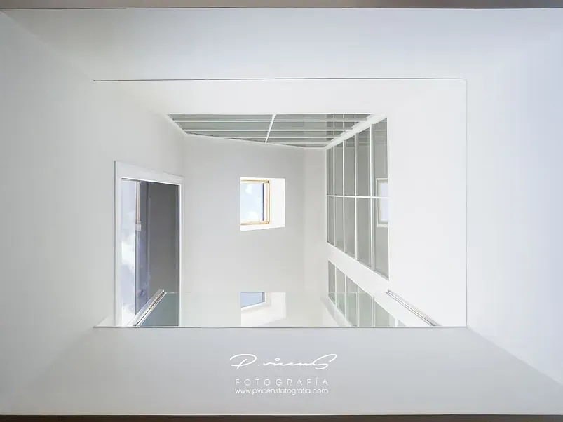 Una imagen de una habitación blanca con una ventana y escaleras.