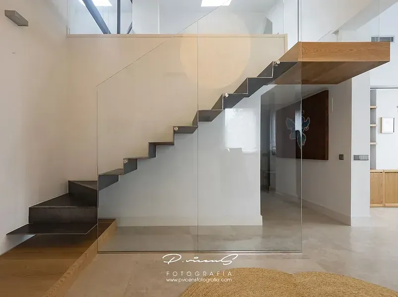 Una escalera moderna con barandilla de cristal en una casa.