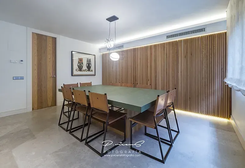 Un comedor con una mesa y sillas verdes.