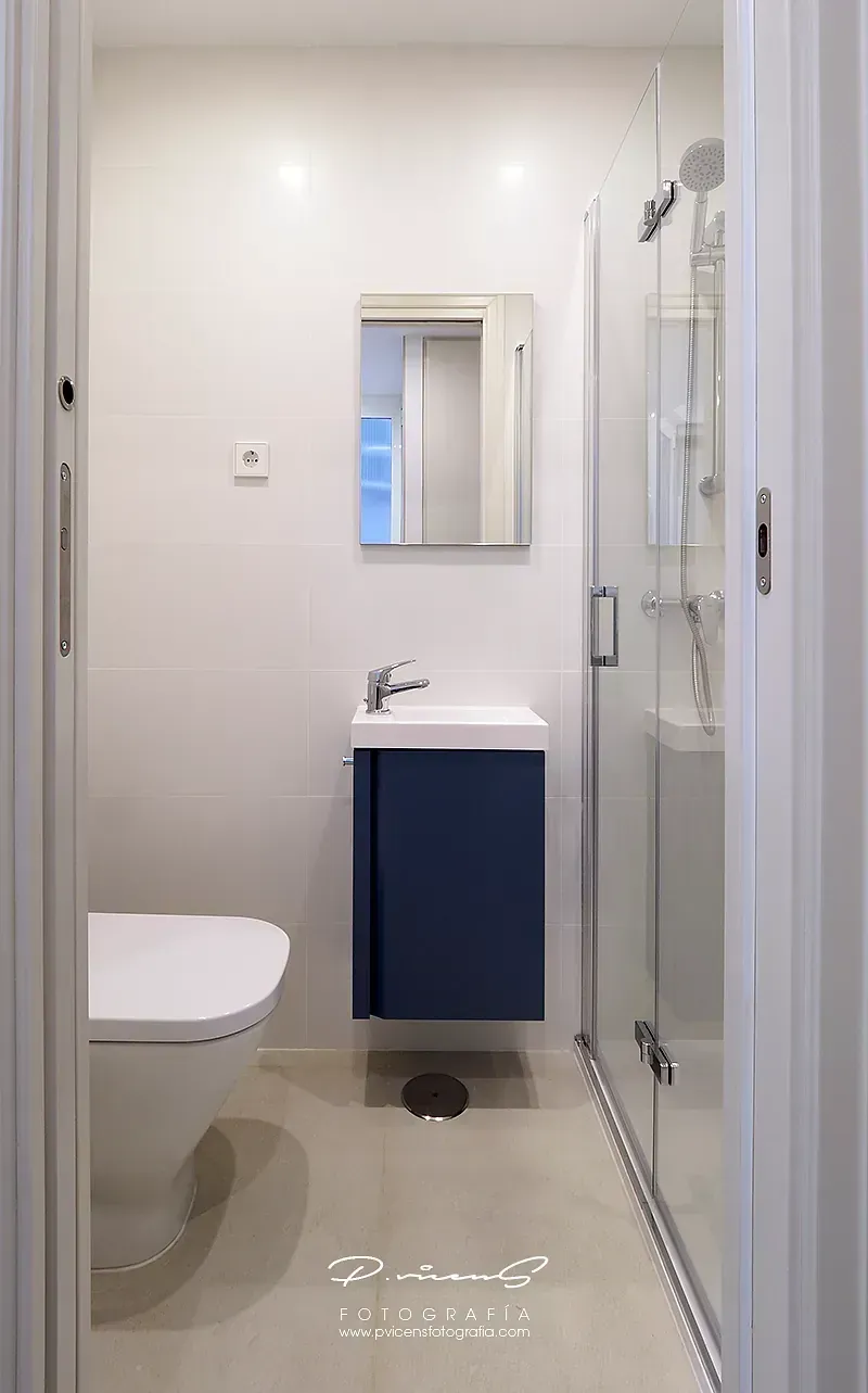 Un baño con inodoro, lavabo, espejo y ducha.