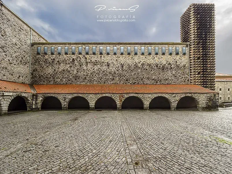 Un gran edificio de piedra con arcos y techo de tejas rojas.