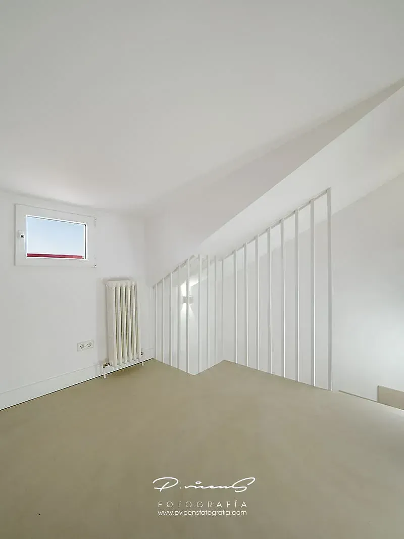 Una habitación vacía con una barandilla blanca y una ventana.