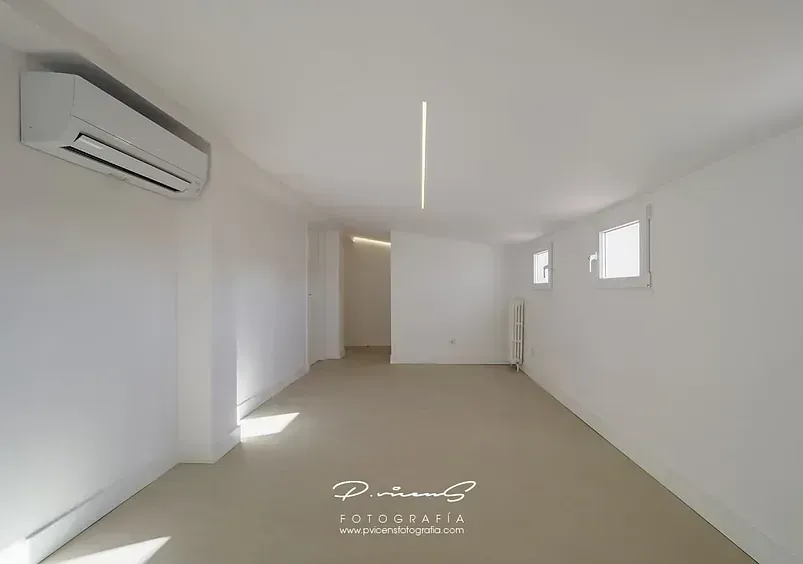 Una habitación vacía con paredes blancas y un ventilador de techo.