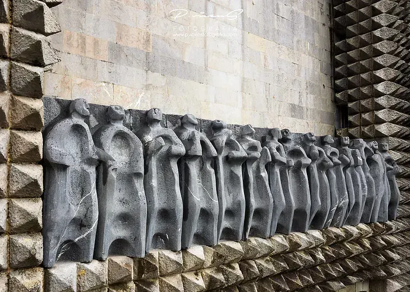 Una fila de estatuas están talladas en una pared de ladrillos.