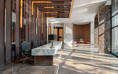 Un gran vestíbulo con una mesa larga y sillas en un hotel.