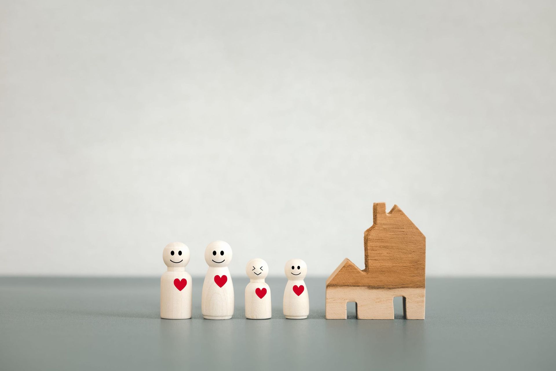 Dos personas sentadas en un sofá besan a un niño en cada mejilla mientras sostienen tazas sobre una mesa blanca