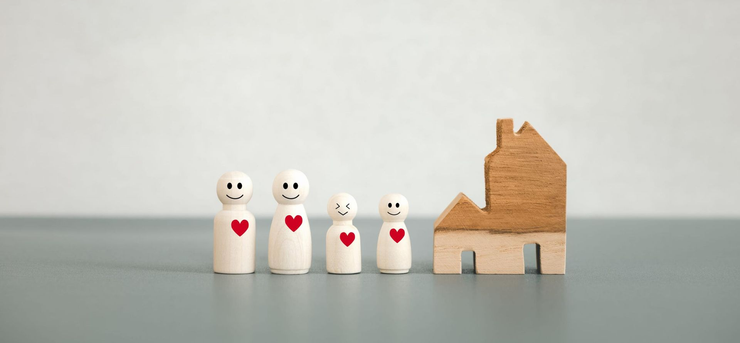 Dos personas sentadas en un sofá besan a un niño en cada mejilla mientras sostienen tazas 