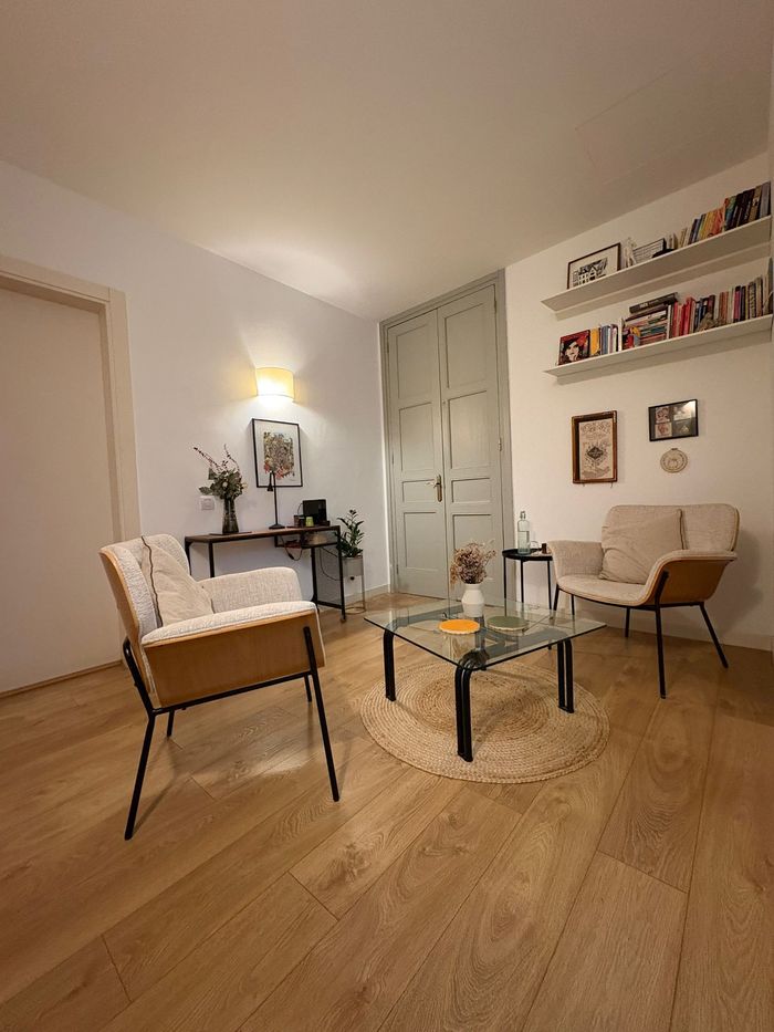 Una persona con una camisa azul claro escribe en un cuaderno mientras está sentada frente a alguien