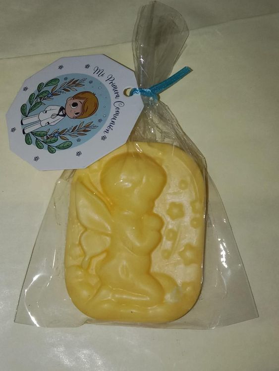 Una pastilla de jabón amarilla con forma de ángel, dentro de una bolsa de plástico transparente con una etiqueta decorativa.