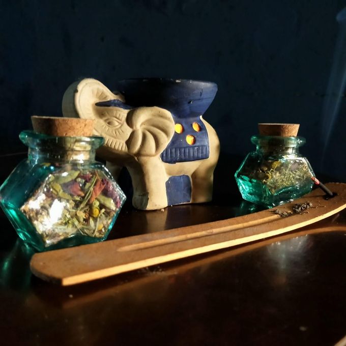 Dos pequeños frascos de vidrio con tapón de corcho, llenos de hierbas secas, se encuentran junto a una figurita de elefante.