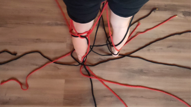 Una persona está parada sobre un piso de madera con un montón de cables alrededor de sus pies.