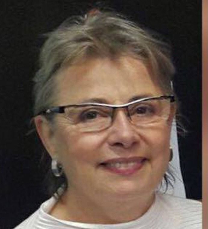 Una mujer que lleva gafas y pendientes sonríe para la cámara.